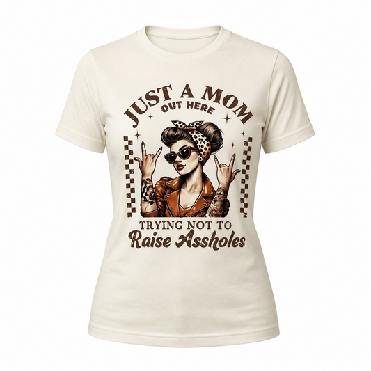 Funny “Just a Mom Out Here Trying Not to Raise Assholes” retro rockabilly graphic t-shirt featuring a tattooed mom wearing sunglasses, a leopard print headband, and a leather jacket.