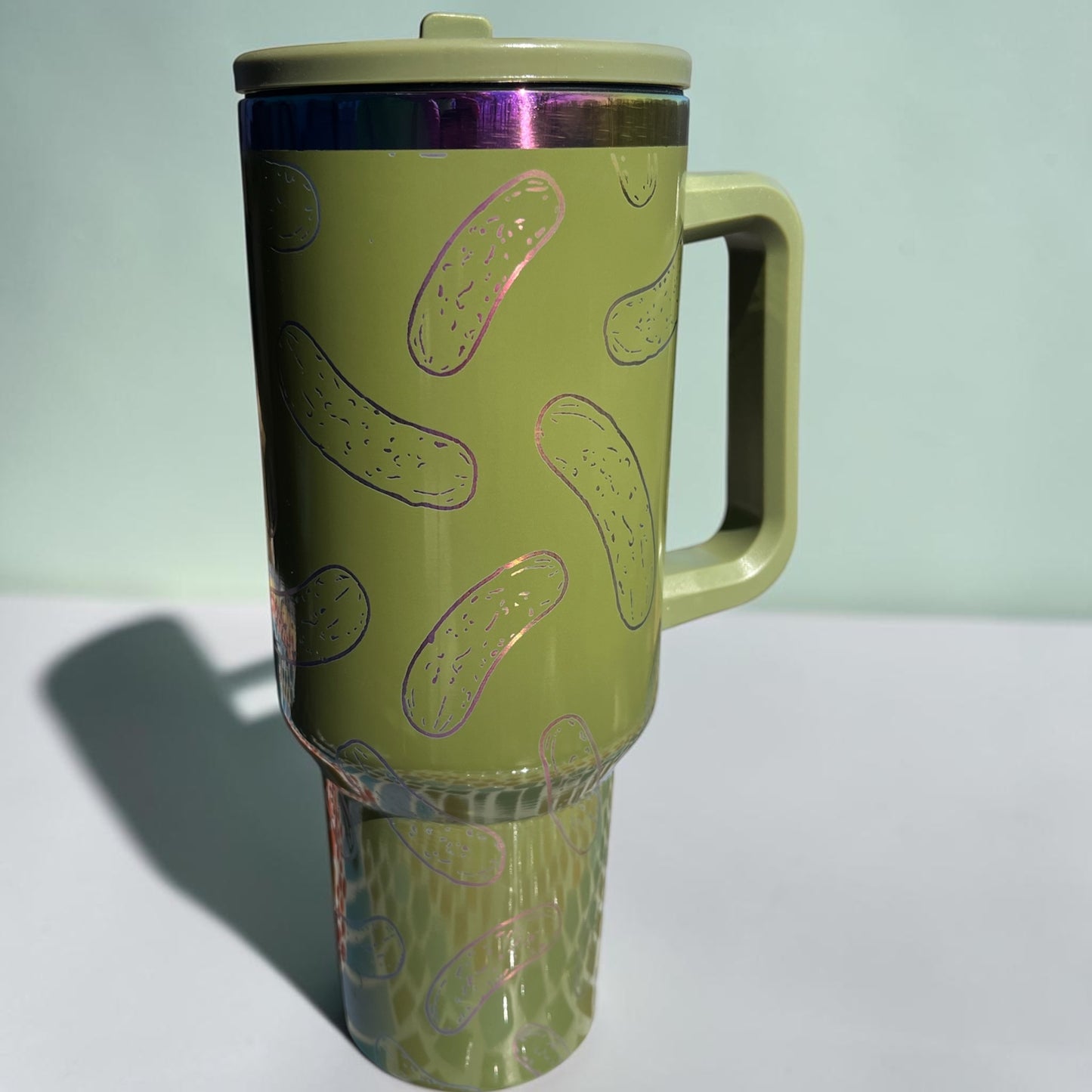 Green travel mug with pickle pattern on a light green background