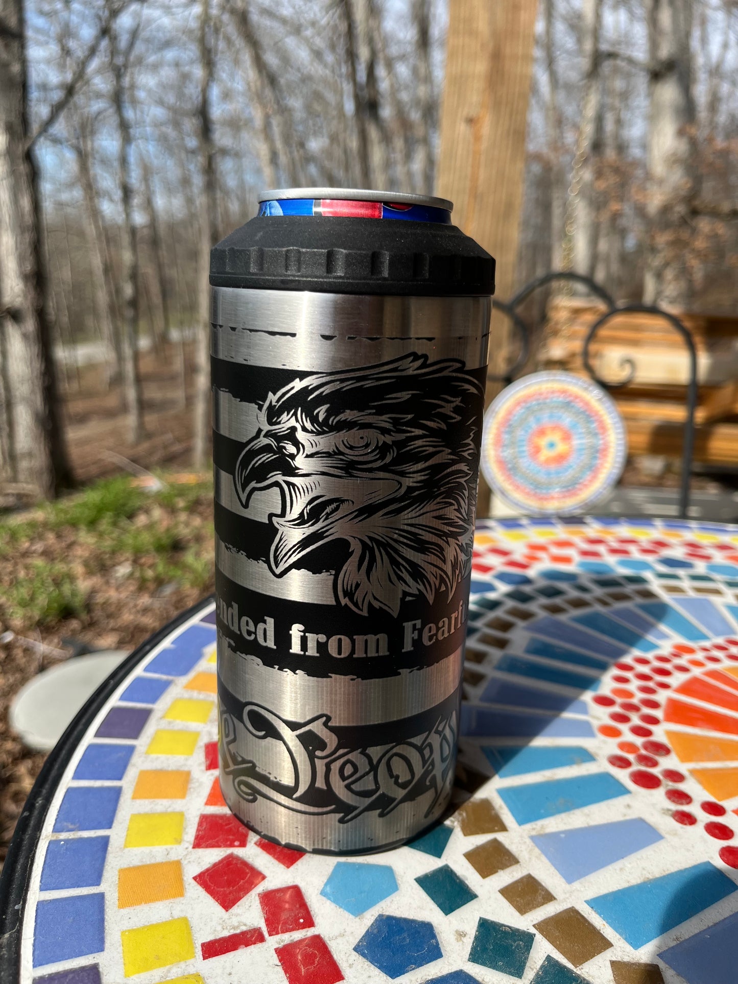 Metal tumbler with engraved design on a mosaic table