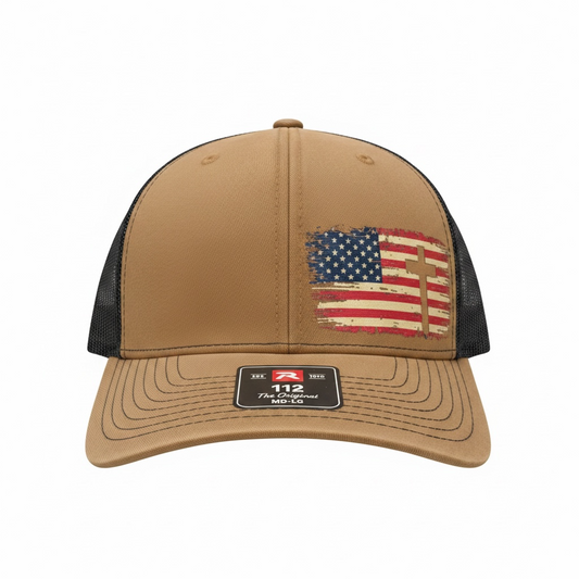 Tan and black Richardson 112 trucker hat featuring a distressed American flag with cross design on the front panel. Faith-based patriotic snapback cap decorated by HandmadeOhio.