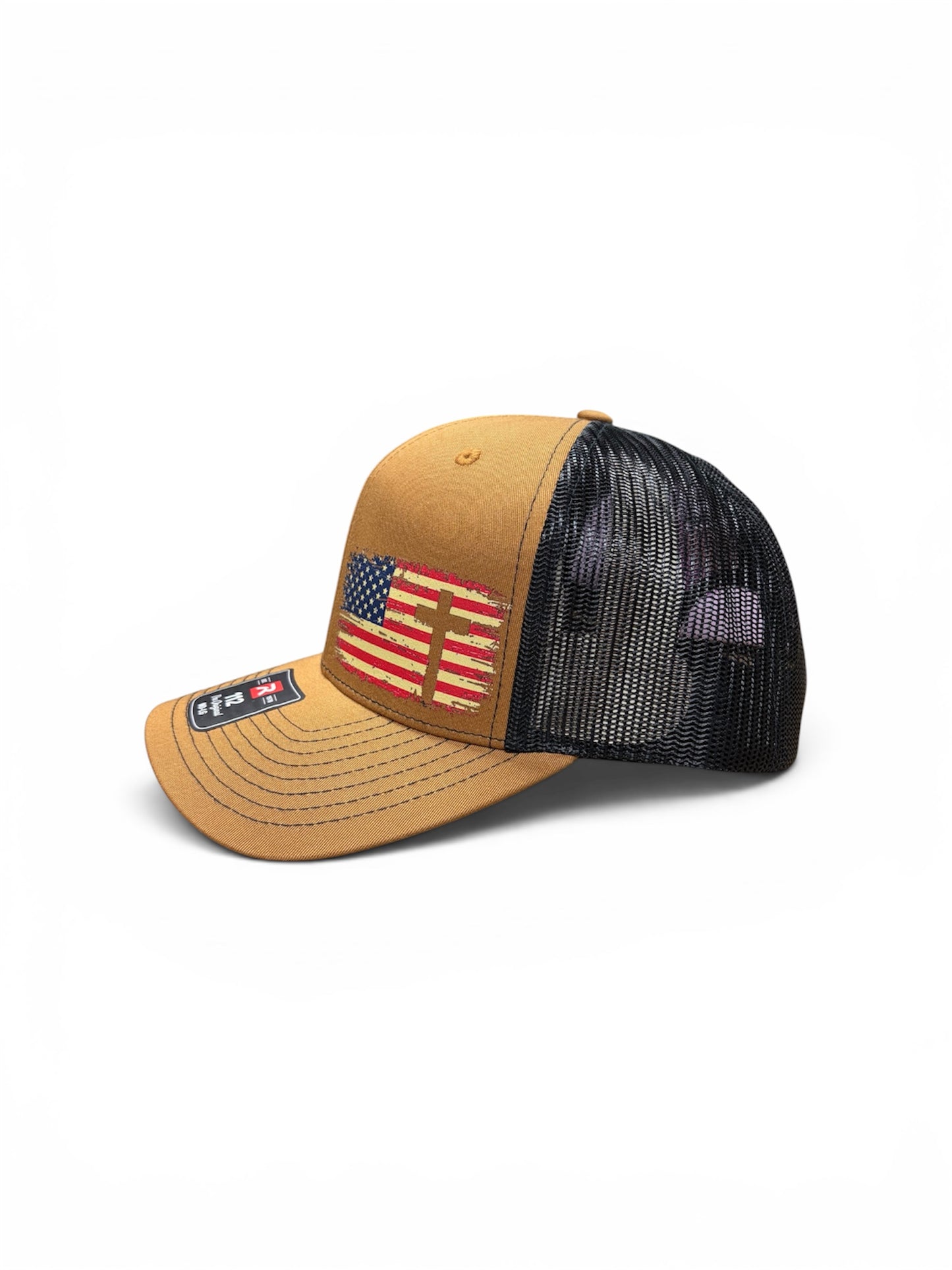 Tan and black Richardson 112 trucker hat featuring a distressed American flag with cross design on the front panel. Faith-based patriotic snapback cap decorated by HandmadeOhio.